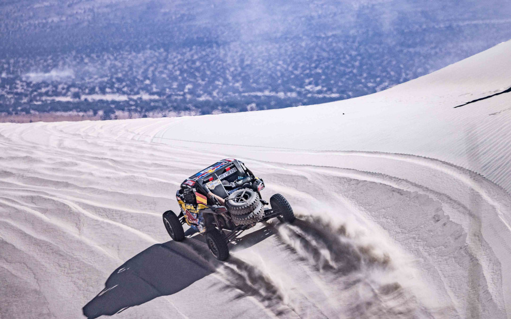 A rally car drives through the desert